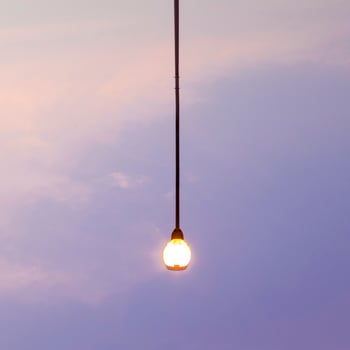 A light bulb hanging from a wire in the sky photo