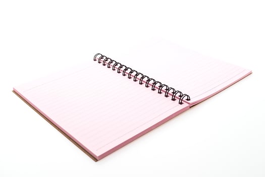 A pink notebook with spiral binding on a white surface photo