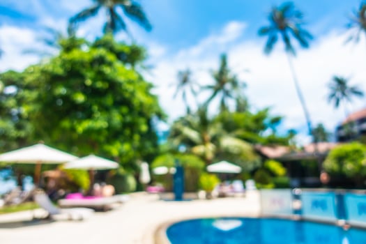 A pool with lounge chairs and umbrellas in front of a resort photo