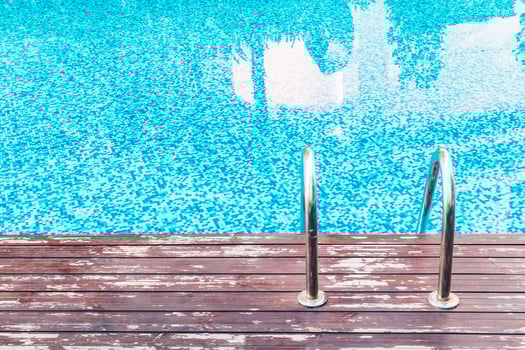 A wooden deck with a pool and a ladder photo