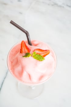 A strawberry milkshake with a straw and a mint leaf photo