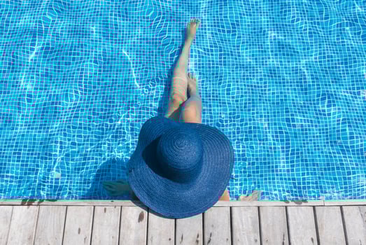 A woman in a blue hat and hat sitting in a pool photo