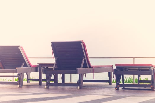 Three lounge chairs on a wooden deck overlooking the ocean photo