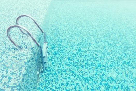 A pool with a ladder and a blue tile floor photo