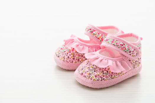 Baby shoes with pink floral print on white background photo