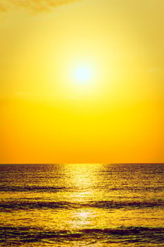 A person on a surfboard riding a wave at sunset photo