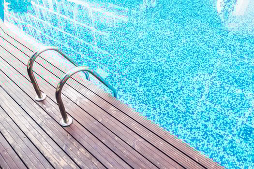 A wooden deck with a pool and a ladder photo