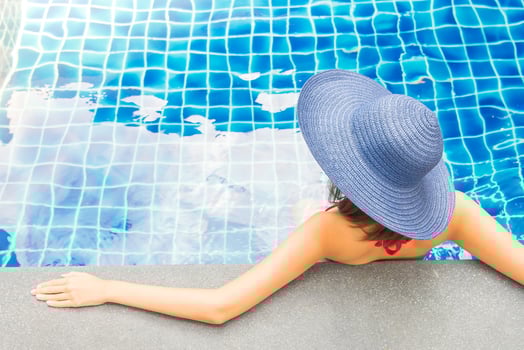 A woman in a blue hat sitting by a swimming pool photo