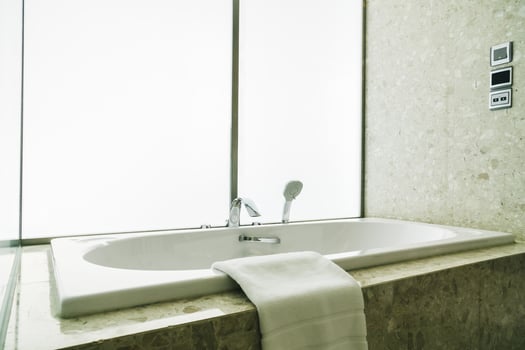 A white bathtub sitting in a bathroom next to a window photo