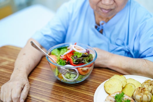 old lady woman patient eating breakfast vegetable healthy food with hope and happy while sitting and hungry on bed in hospital. photo