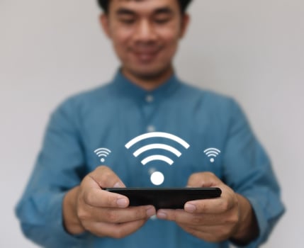 Young handsome wearing a light blue shirt turn use smarthphone connected to Wi-Fi technology for using smart home function. Technology business and modern lifestyle concept. photo