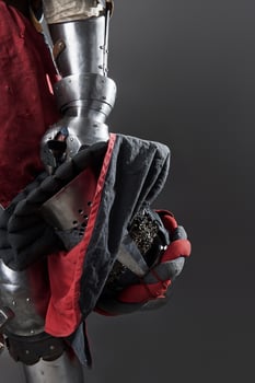 Medieval knight on grey background. Portrait of brutal dirty face warrior with chain mail armour red and black clothes and battle axe photo
