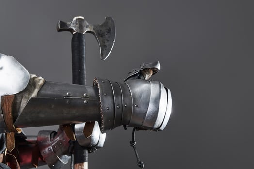 Medieval knight on grey background. Portrait of brutal dirty face warrior with chain mail armour red and black clothes and battle axe photo