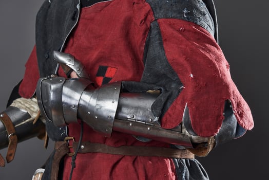 Medieval knight on grey background. Portrait of brutal dirty face warrior with chain mail armour red and black clothes and battle axe photo