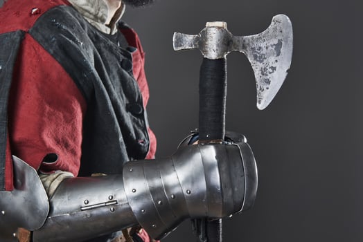 Medieval knight on grey background. Portrait of brutal dirty face warrior with chain mail armour red and black clothes and battle axe photo