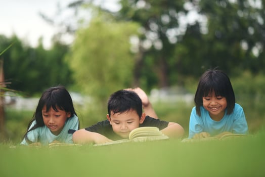 Group of children lying reading on grass field photo