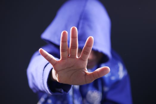 sad man in hood cover face with hands isolated in black. photo