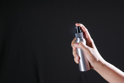 young man hand hold a body spray isolated on black photo