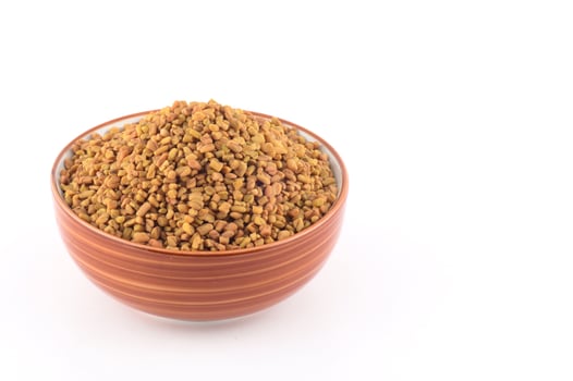 Fenugreek seeds in bowl isolated on white background photo