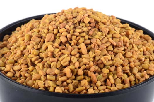 Fenugreek seeds in bowl isolated on white background photo