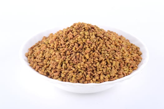 Fenugreek seeds in white plate isolated on white background photo