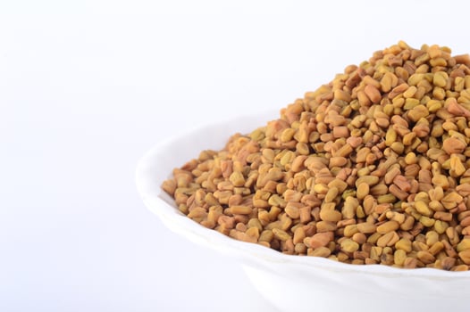 Fenugreek seeds in white plate isolated on white background photo