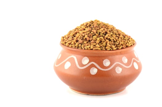 Fenugreek seeds in clay pot isolated on white background photo