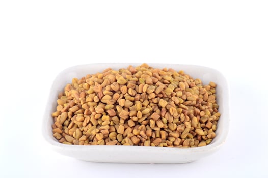 Fenugreek seeds in white plate isolated on white background photo
