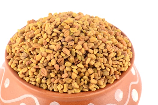 Fenugreek seeds in clay pot isolated on white background photo