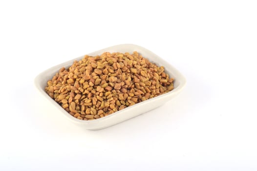 Fenugreek seeds in white plate isolated on white background photo