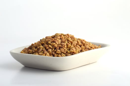 Fenugreek seeds in white plate isolated on white background photo