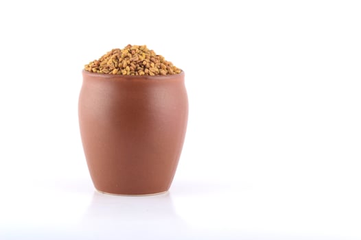 Fenugreek seeds in clay pot isolated on white background photo