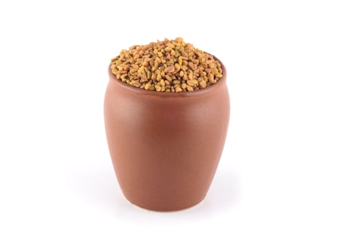 Fenugreek seeds in clay pot isolated on white background photo