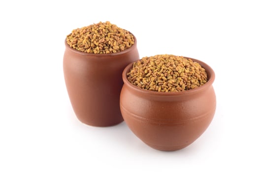 Fenugreek seeds in clay pot isolated on white background photo