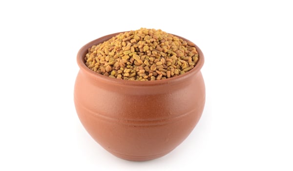 Fenugreek seeds in clay pot isolated on white background photo