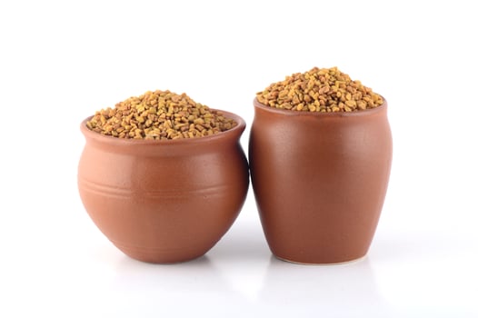 Fenugreek seeds in clay pot isolated on white background photo