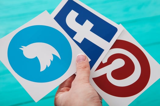 KIEV, UKRAINE - MARCH 10, 2017. Facebook , Pinterest, Twitter logos printed on paper in woman hand on blue wooden background. Selective focus photo