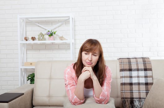 Depressed and sad middle aged woman sitting on bed, coach, sofa at home. Copy space and mock up. photo