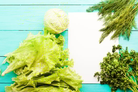 Different vegetables on kitchen table with recipe list and copy space. Top view photo