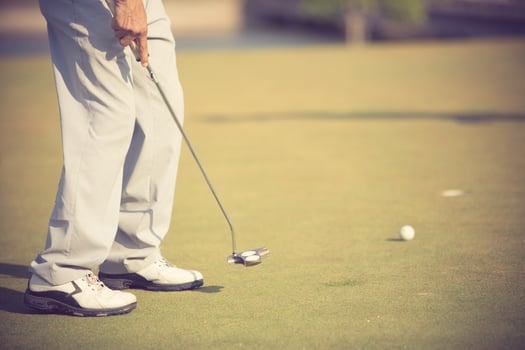 Golf player at the putting green hitting ball into a hole.Vintage color photo