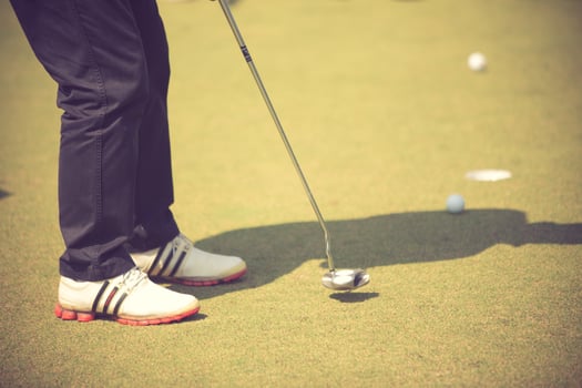 Golf player at the putting green hitting ball into a hole.Vintage color photo