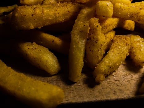 Close up photo of french fries on a wooden cutting board.