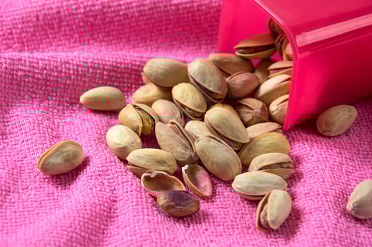 Pistachios in container on pink background photo