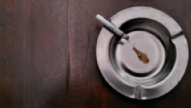 Defocused background cigarettes and ashtray on vintage wooden table with copy text space. photo