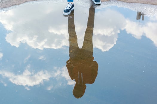 Reflection in water of man with casual style standing in bright blue sky photo