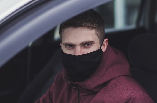a man driving a car in black protective mask photo