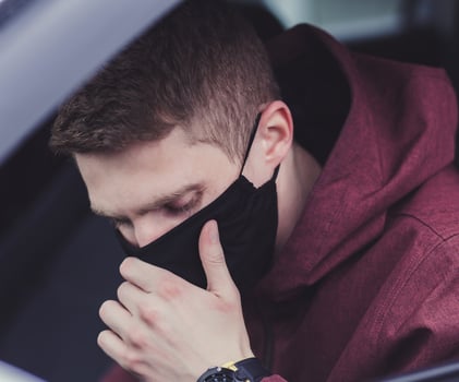 Man driver in a black mask coughs photo