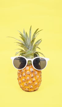 pineapple in glasses isolated on a yellow background photo