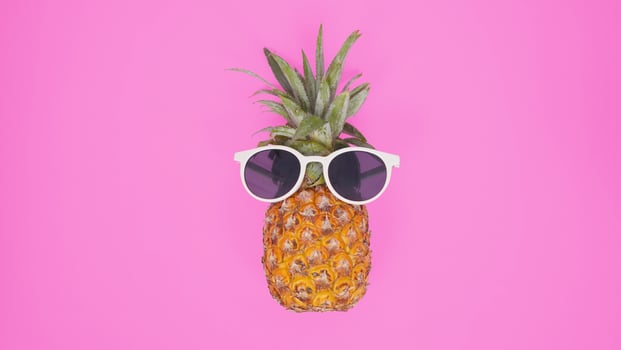 Pineapple with glasses isolated on a pink background photo