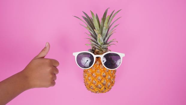 pineapple fruit with glasses and thumb isolated on pink background photo
